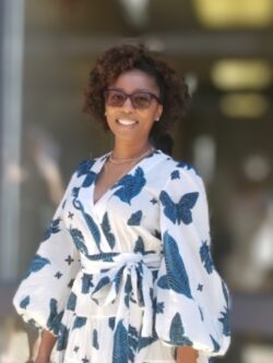 Photo of Jacqueline Davis smiling, wearing a white and blue dress