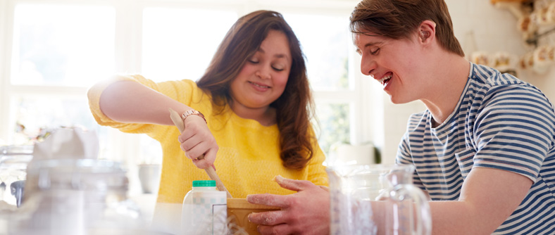 Image of Young Downs Syndrome Couple Baking In Kitchen At Home