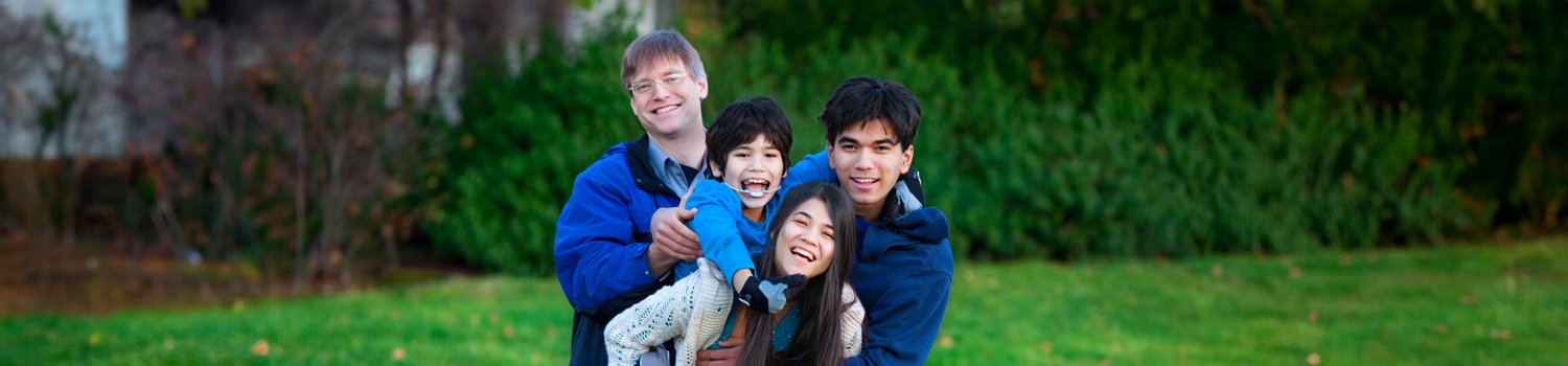Disabled child with his family holding him, together at park.