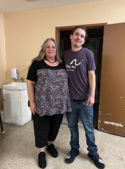 A man and woman are standing together for a group photo and smiling