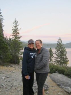 Two sisters smiling together outdoors in front of Lake Tahoe