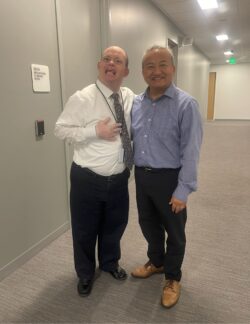 Two men smiling together in a hallway