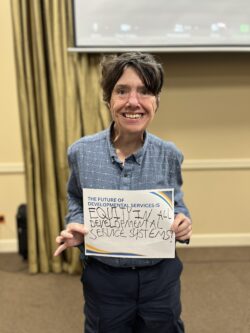 woman named kecia holding a sign in a large yellow conference room