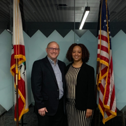 Pete and JaRita smile together between the state and US flag