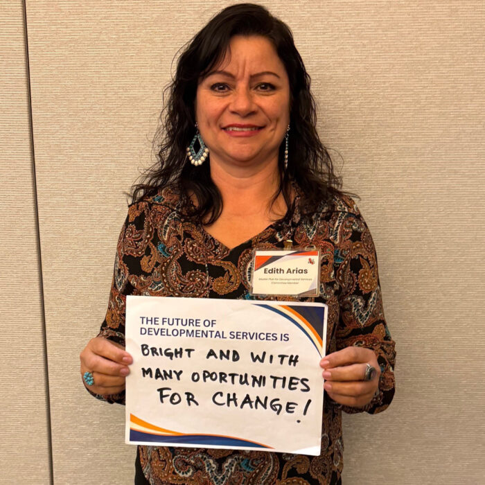Master Plan committee member Edith Arias smiles at the camera while holding a sign that reads: The Future of Developmental Services is bright and with many opportunities for change!"
