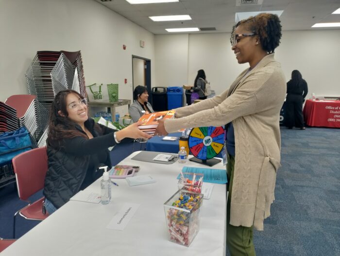 Office of the Self-Determination Program Ombudsperson representative Jacqueline Davis giving Lanterman Consumer Guides to SDP service provider Community Builders.
