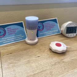 Two signs on a bedside table discuss the bed shakers, strobe lights, and alarm clocks in the room