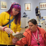 Elin Herval showing a book to a lady who's sitting