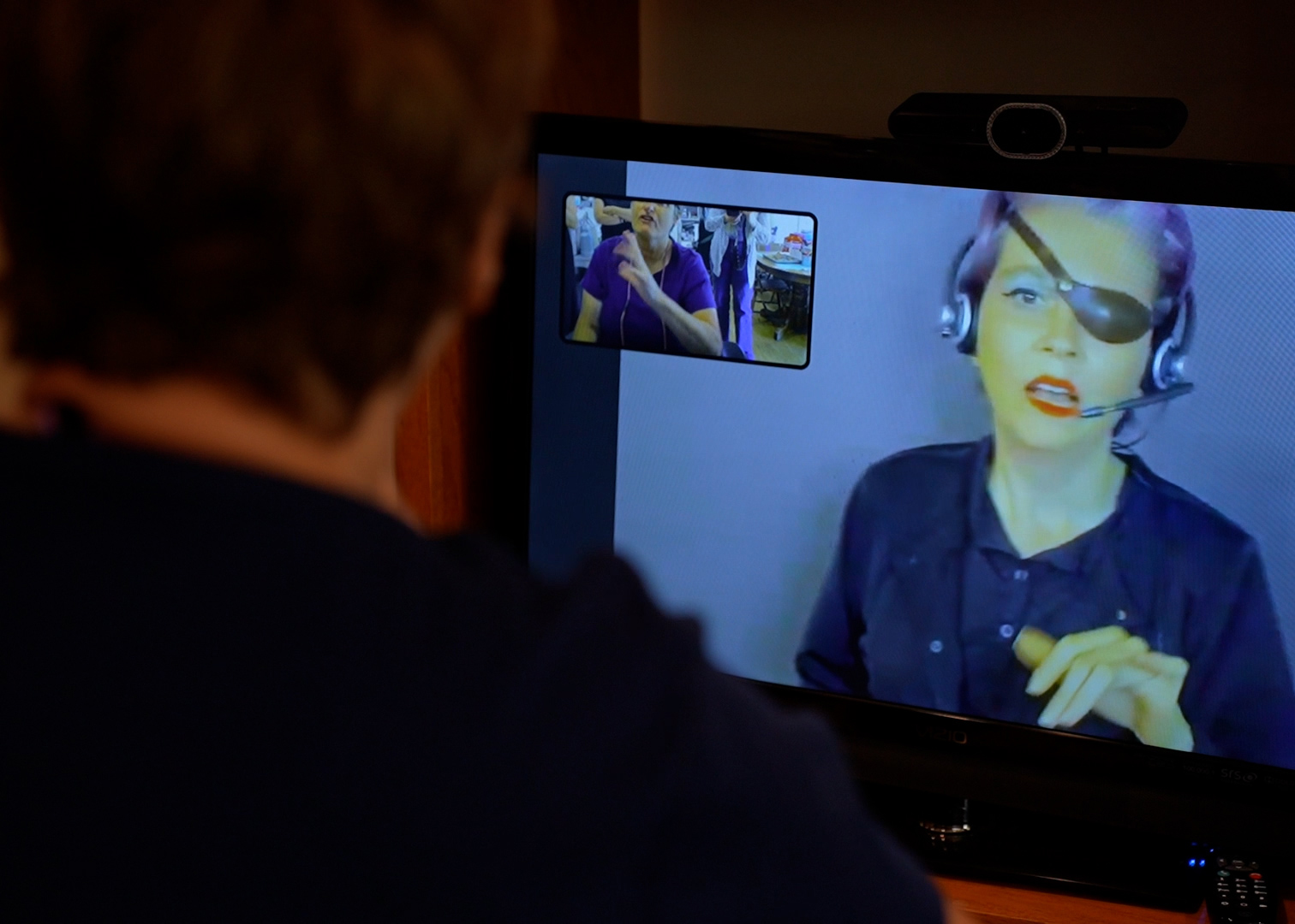 Woman signs to another woman who is in a monitor