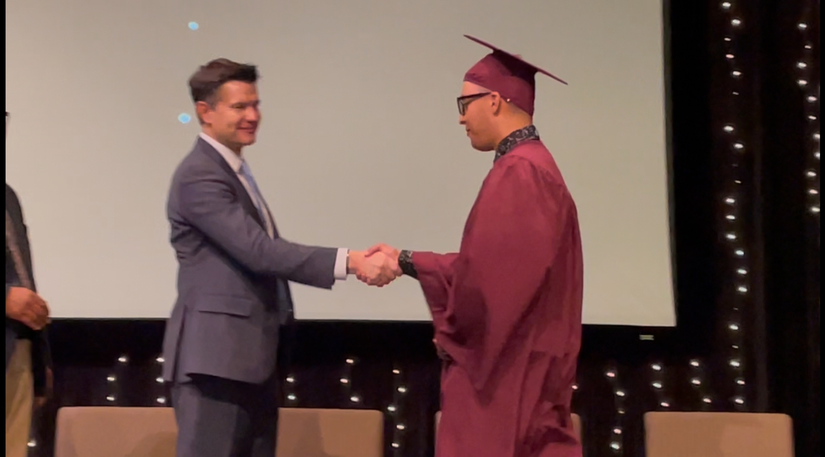 Noah receives his diploma during graduation ceremony.